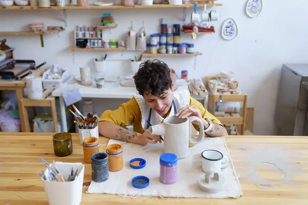 年轻而快乐的女艺术家在艺术课上专心致志于绘画和装饰陶器 — 图库照片
