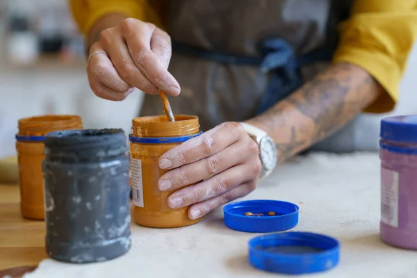 Closeup de artesã mão segurando pintura e pincel se preparando para decorar cerâmica artesanal — Fotografia de Stock