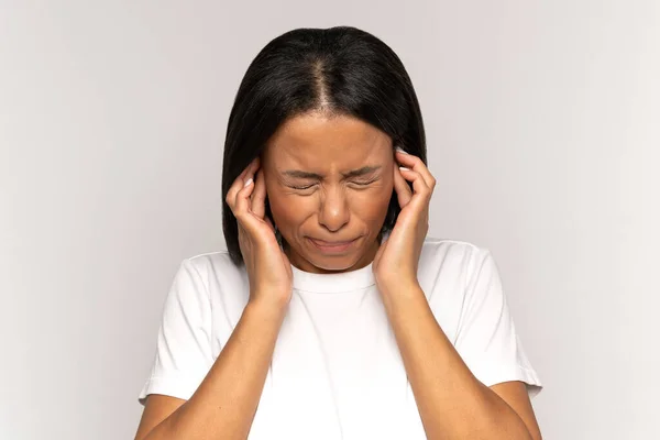 Annoyed stressed female cover ear avoid noisy sound, suffer from headache, anxiety or mental problem