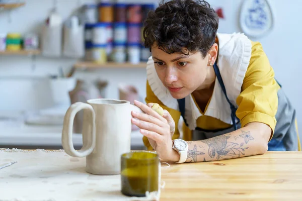 Umělecká hrnčířka pracuje v džbánu sochařské misky s nářadím pro keramiku v ateliéru nebo dílně — Stock fotografie