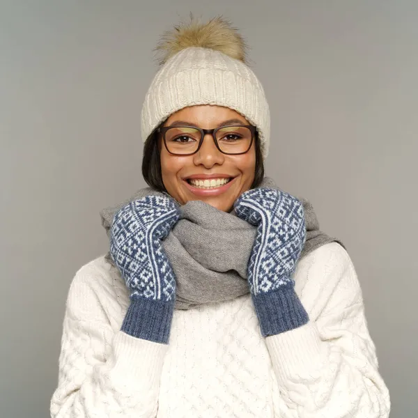 Teplé zimní oblečení: šťastná usměvavá černoška v pleteném bílém svetru, klobouku, rukavicích a šále — Stock fotografie