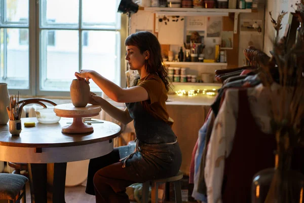 Kobieta rzemieślniczka siedzi w pracowni rzeźbiąc wazon. Bizneswoman relaks po pracy w warsztacie — Zdjęcie stockowe