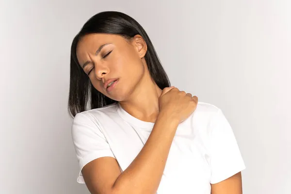 Vermoeide vrouw masseert pijnlijke schouder en nek. Uitgeputte vrouw lijdt aan spier spam in de rug — Stockfoto