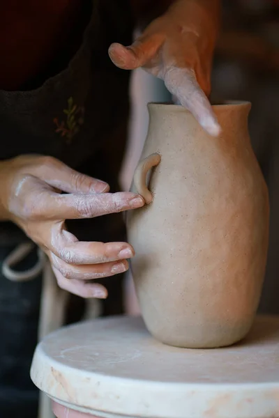 Работа с сырой глиной: мастер керамики добавляет детали в горшечную вазу кувшина. Художественное занятие в студии — стоковое фото