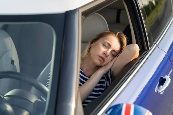 Женщина устала водить машину спать на переднем сиденье. Женщина путешествует на машине, отдыхает внутри — стоковое фото