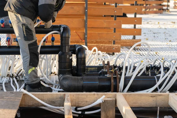 Sistema de tubulação de construção de trabalhadores para manutenção de baixa temperatura. Preparação da pista de patinação ao ar livre — Fotografia de Stock
