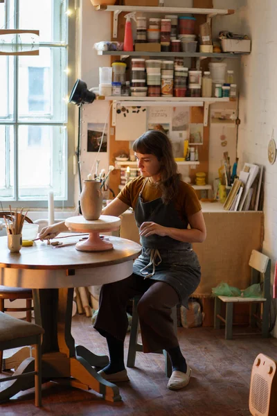 Maître de poterie sur le lieu de travail : femme assise à la table dans le travail de studio avec de l'argile brute pour créer pot de potier — Photo