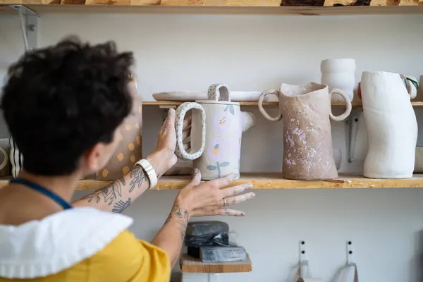 Artística hembra ceramista poner jarra decorada con ornamento dibujado a mano en el estante con cerámica hecha a mano — Foto de Stock