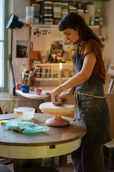 Молодий виробник гончарних виробів працює з глиною на гончарному колесі в творчому просторі або професійній студії — стокове фото