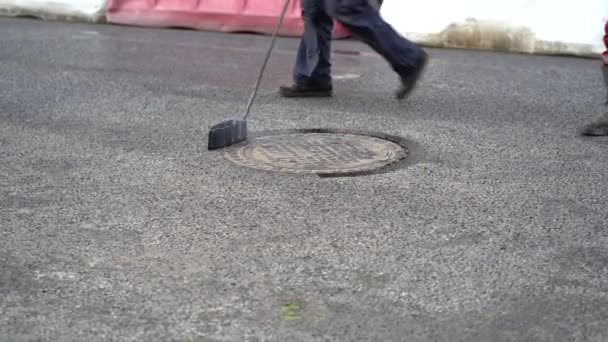 I lavoratori versano bitume fuso da un secchio lungo il tombino dopo aver pavimentato nuovo asfalto sulla strada — Video Stock