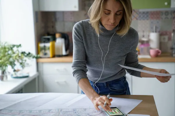 Zajęta kobieta architekt pracuje nad szkicem projektu z planem budynku na tablecie cyfrowym z domu — Zdjęcie stockowe