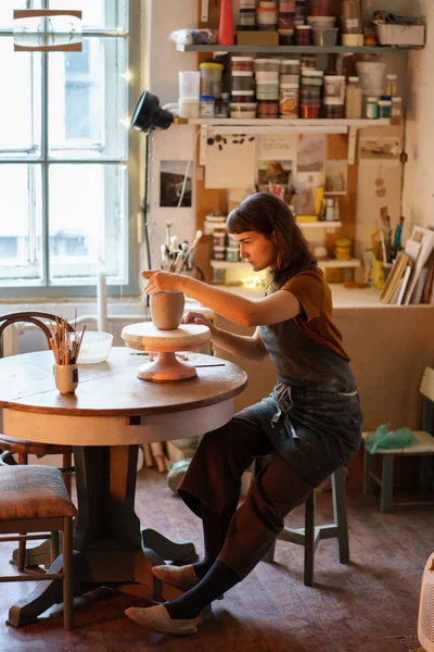 Céramiste en vase de moulage de tablier en master class en studio. Jeune femme propriétaire d'un studio de poterie au travail — Photo
