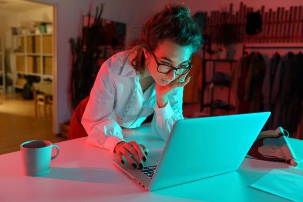 Jonge vrouwelijke kleding ontwerper werk op laptop in atelier studio lees zakelijke e-mail en het maken van bestellingen — Stockfoto