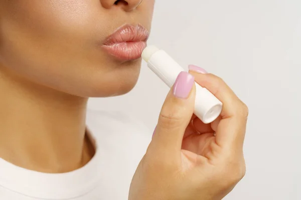 アフリカの女性は唇の保湿と寒さや風からの保護のための衛生的なバルサム口紅を適用します — ストック写真