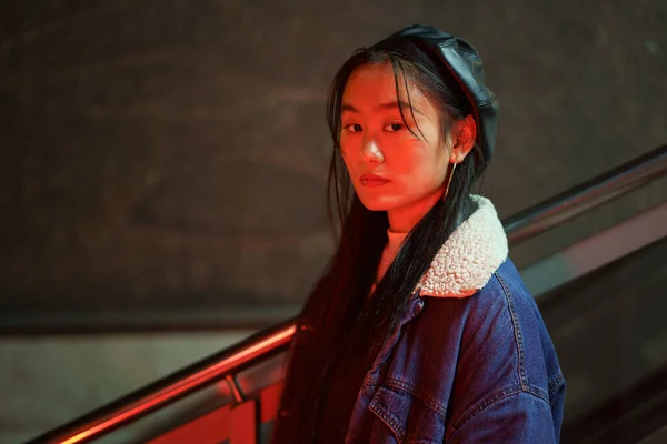 Stylish korean girl in trendy outfit and leather beret. Young asian female at neon city light