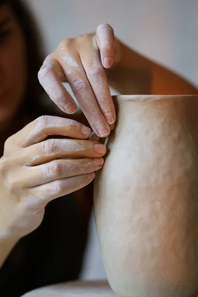 Ремесленничество: женщина-ремесленница, работающая с мокрой глиной, украшающей кувшин в керамической мастерской — стоковое фото