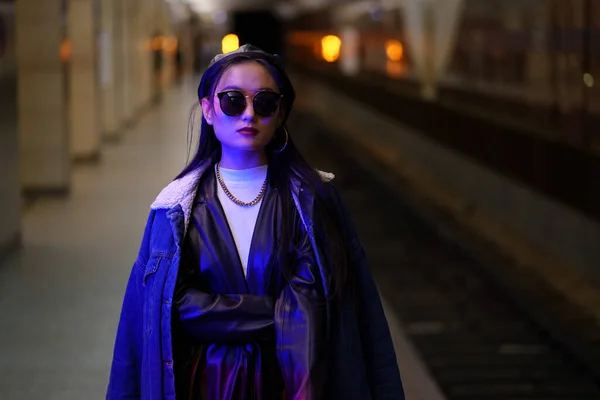 Chica hipster coreana en gafas de sol de moda esperar a que el tren en la plataforma de metro de la ciudad viaje en metro — Foto de Stock