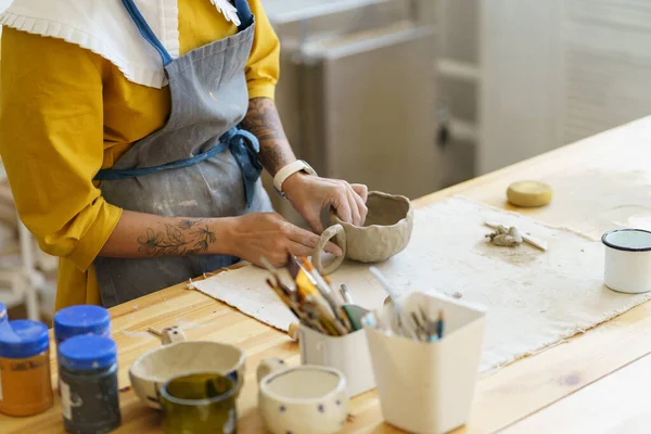 Жінка в фартусі, що формує кераміку в художній студії, робить глиняний кухоль під час майстер-класу з кераміки — стокове фото