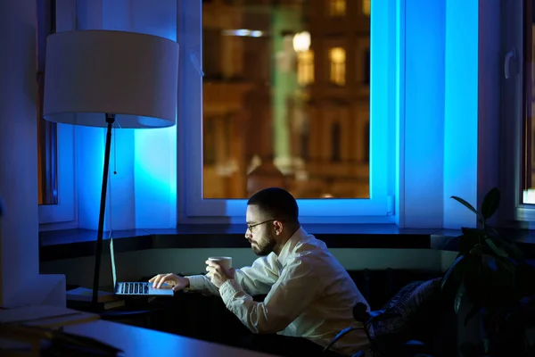 Unavený webdesigner strávit noc v práci před zahájením projektu pracuje na notebooku a pití kávy — Stock fotografie