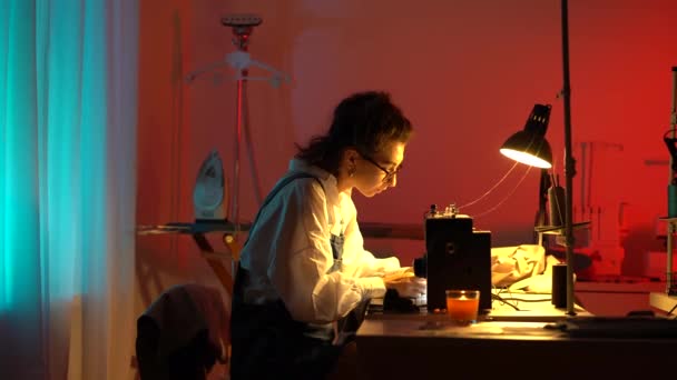 Mulher costureira criativo designer de moda trabalho tarde da noite no estúdio costurar roupas na máquina de costura — Vídeo de Stock