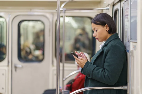 Sosyal medyadan bağımlı Afrikalı bir kız işe ya da eve metroyla giderken akıllı telefon kaydırıyor. — Stok fotoğraf