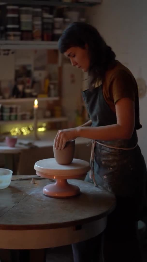 Pottery řemeslné hobby. Uvnitř keramiky studio s mladou ženou tvarování hliněné sklenice na lekci — Stock video