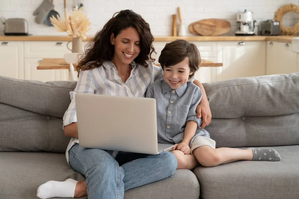 Joyeux jeune maman et fils regarder vidéo drôle sur ordinateur portable, ont appel assis ensemble sur le canapé à la maison — Photo