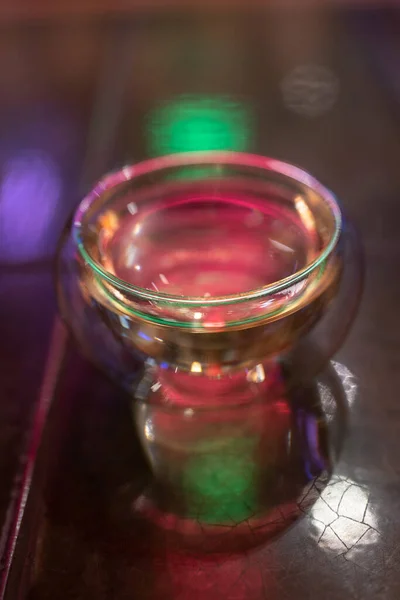 Artículos de vidrio para bebidas calientes sobre fondo borroso, luz de neón colorida. Taza limpia. — Foto de Stock