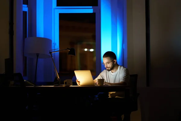 Zamyšlený mladý podnikatel v brýlích práce na notebooku v noci přípravy na start-up prezentace — Stock fotografie