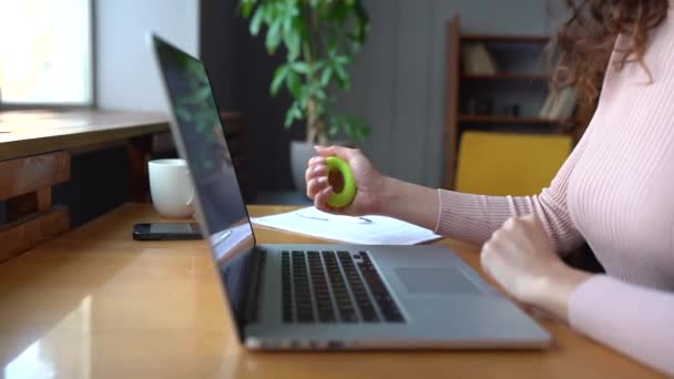 Empresaria u oficinista aprieta un expansor de goma en la mano después de trabajar en el ordenador portátil — Vídeo de stock