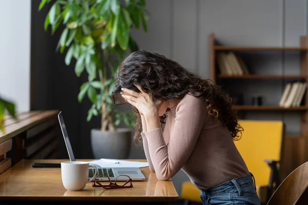Mujer infeliz agotada sentarse en el ordenador portátil ocultar la cara en las manos cansada trabajar horas extras sufren de agotamiento — Foto de Stock