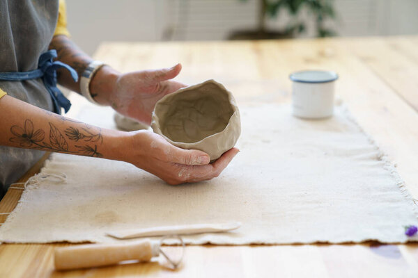 Woman potter sculpting clay pot with hand. Ceramist work with raw earthenware creating craft pottery