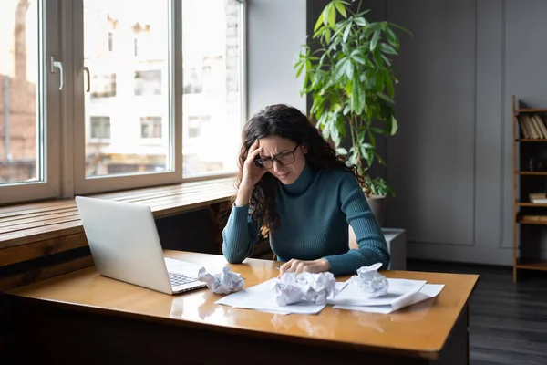 Перевантажена втомлена бізнес-леді сидить за столом з ноутбуком і розчарований папір розчарований і виснажений — стокове фото