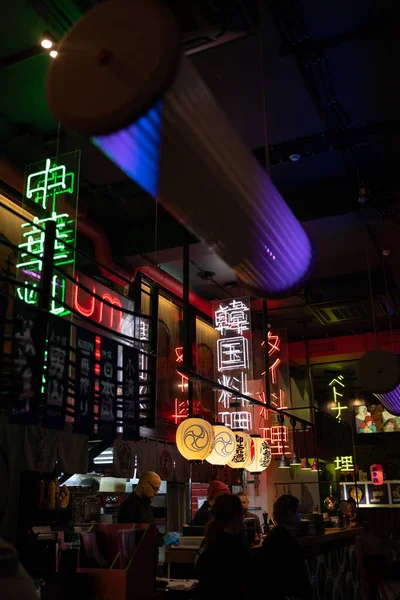 Les gens qui mangent dans un restaurant chinois moderne à la mode décoré de lanternes en papier et de hiéroglyphes au néon — Photo