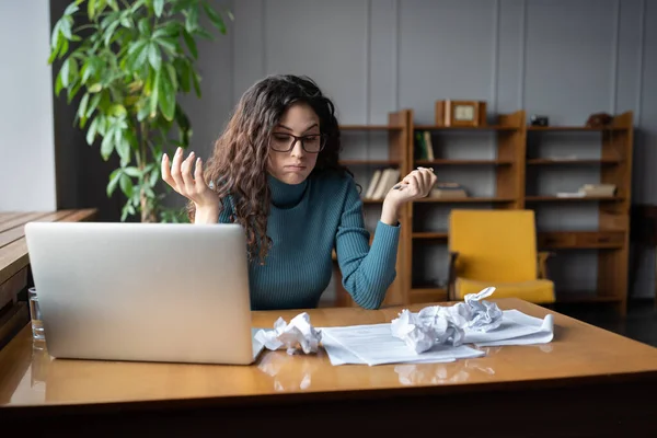 Стрессовая деловая женщина сидит за рабочим столом с мятой бумагой, не может справиться с крайним сроком на работе — стоковое фото