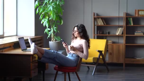 Jonge zelfstandige zakenvrouw ontspannen van het werk op de laptop op het bureau drinken koffie surfen sociale media — Stockvideo