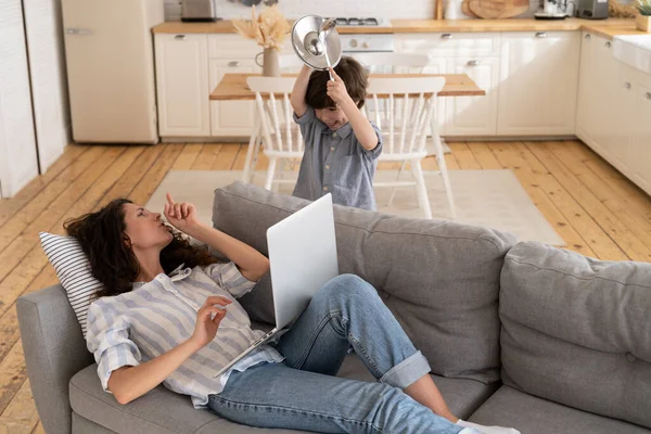 Overwhelmed mom ask son to be silent surfing internet for work. Parent and child on covid lockdown — Stock fotografie