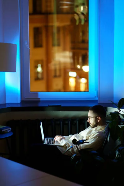 Unavený programátor v temné kanceláři pracuje na laptopu. Workoholik podnikatel psaní na počítači v noci — Stock fotografie