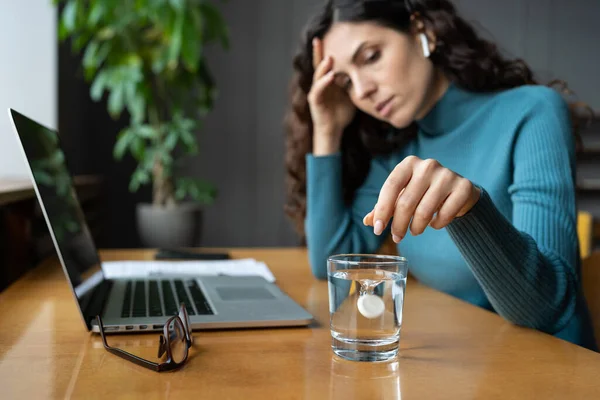 Unhealthy woman suffer from headache migraine in office dissolving aspirin painkiller pill in water — Stockfoto