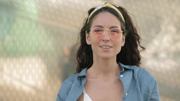 Happy millennial woman in trendy hipster outfit and glasses look in camera with joyful tender smile — Vídeo de stock