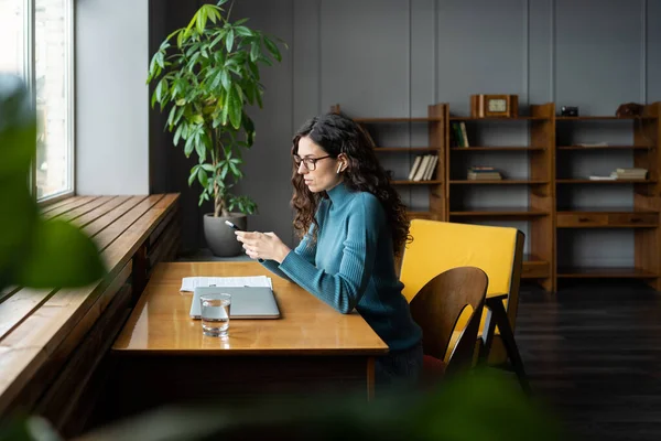 Mulher copywriter freelancer usando smartphone para verificar as mídias sociais no local de trabalho trabalhando remotamente — Fotografia de Stock