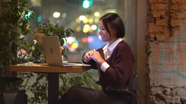 Young friendly afro american woman tutor working remotely in cafe, giving online lesson via laptop — Stockvideo