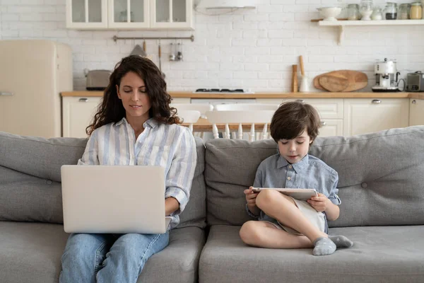 Mother freelance worker use laptop and preschool son play games on digital tablet together at home — Stock Photo, Image