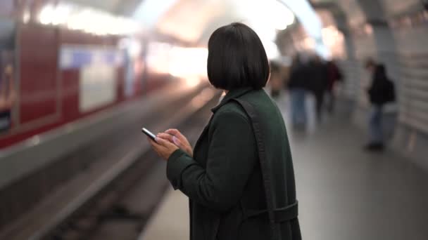地下鉄のホームでスマートフォンを使用している深刻なアフリカの実業家地下鉄の列車を待っている間 — ストック動画
