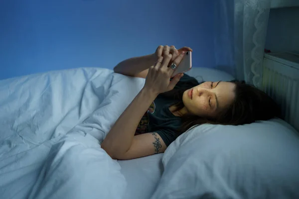 Mulher que sofre de transtorno de vício na internet, insônia. Feminino usando smartphone na cama à noite — Fotografia de Stock