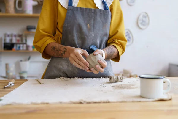 Artista alfarera femenina manos moldeando arcilla cruda. Mujer ceramista en delantal prepararse para dar forma a la cerámica — Foto de Stock