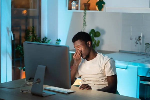 長時間のコンピュータ使用中に眼の緊張と疲労を感じるアフリカの男の過労 — ストック写真
