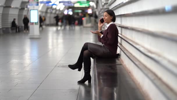 地下鉄駅で楽しいアフロ女性が電話で話す公共交通機関のプラットフォームで電車を待つ — ストック動画