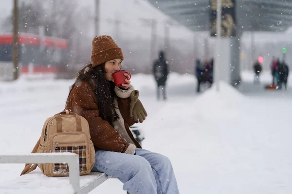 Chica viajera joven beber té caliente en la estación de tren esperar a la salida del transporte para las vacaciones de invierno —  Fotos de Stock