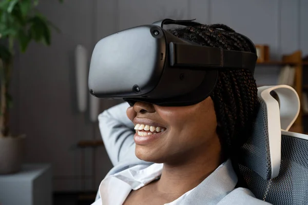 Happy relaxed afro woman in VR googles using virtual reality to relax and reduce stress at workplace — Stock Photo, Image